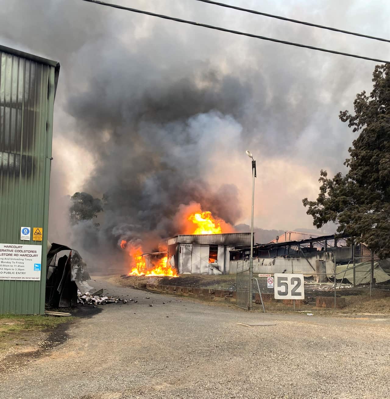 A building in an industrial state has flames and smoke pouring from the roof.