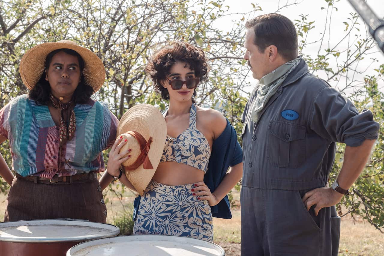 2 women are talking to a man in an apple orchard