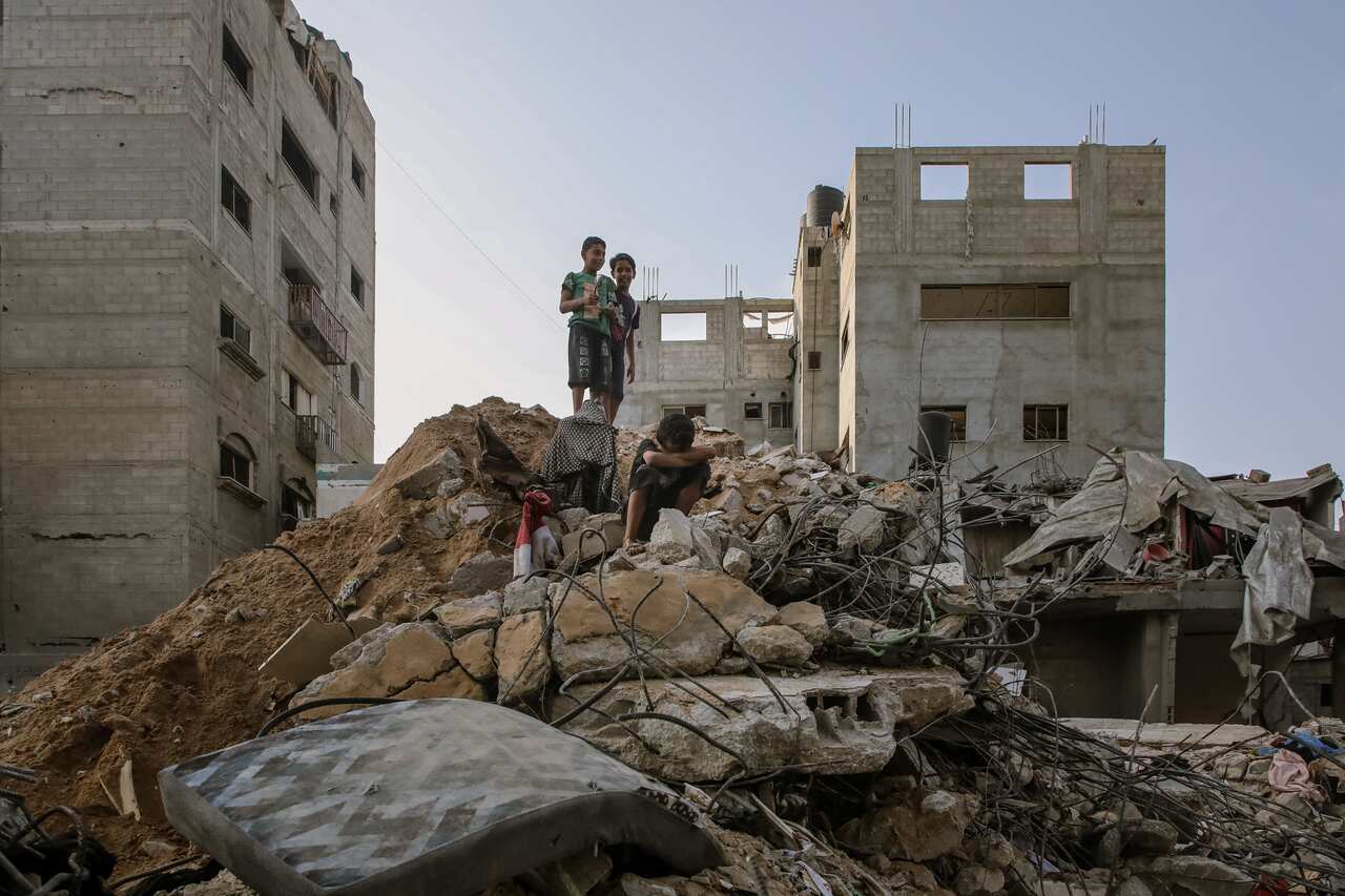 Three children stand on rubble.