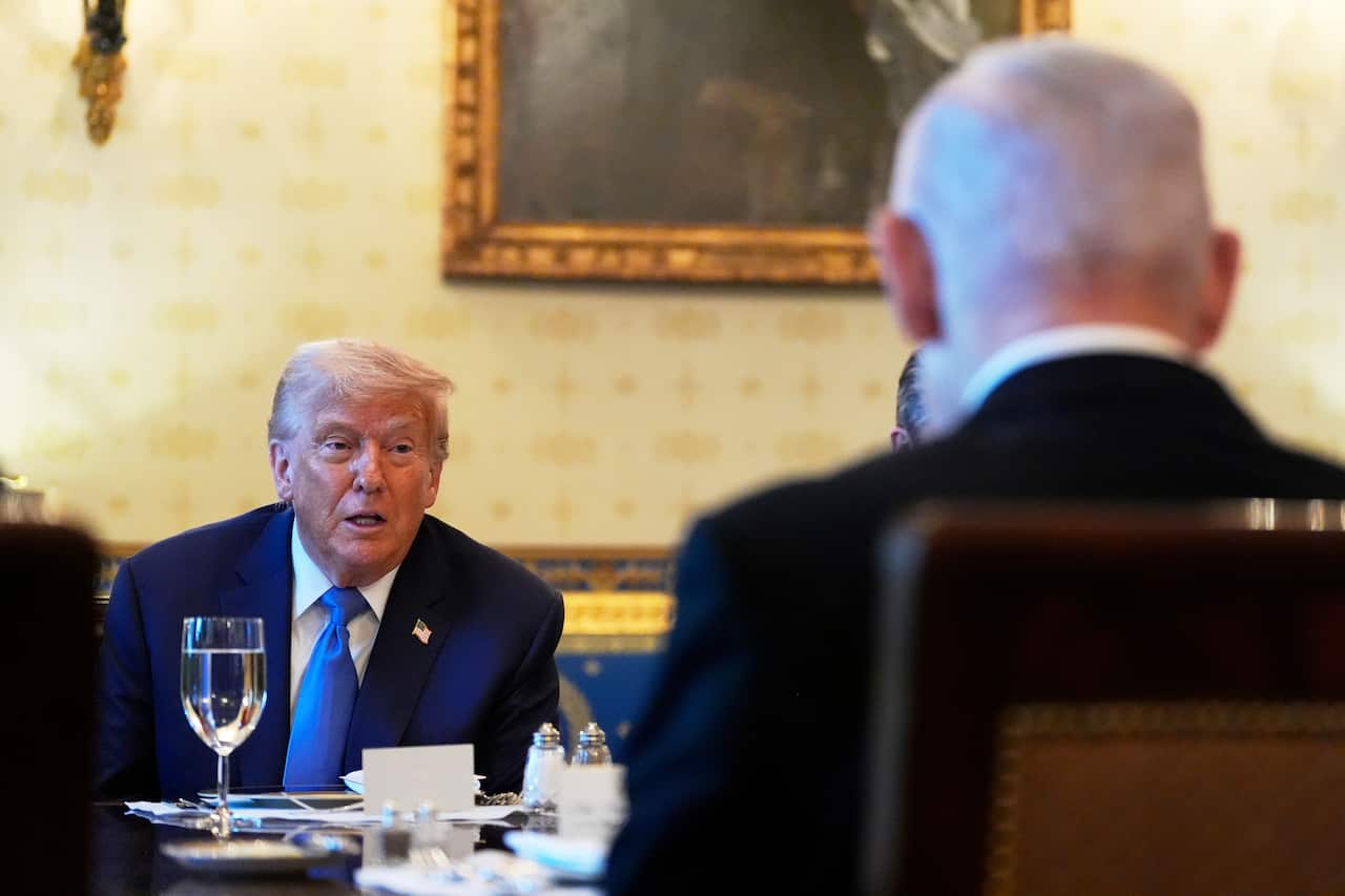 Donald Trump seated at a table. Benjamin Netanyahu's back is visible.