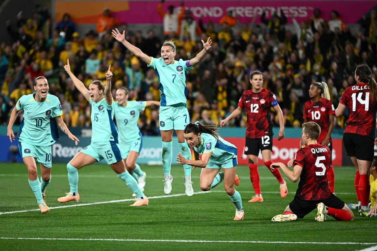 Two groups of women footballers - in blue and red jerseys - reacting after a goal.