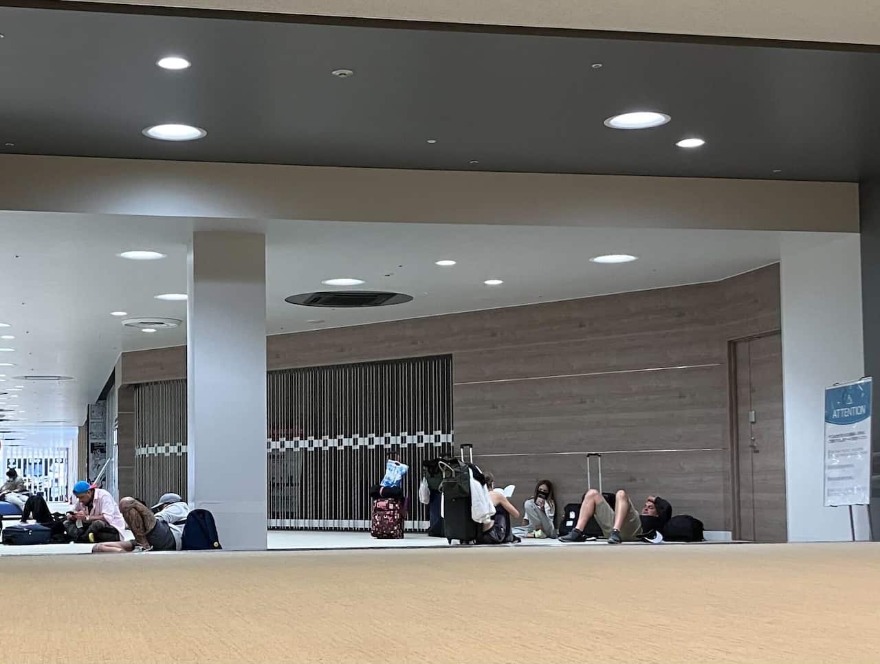 Passengers sitting down as they are stuck at an airport.