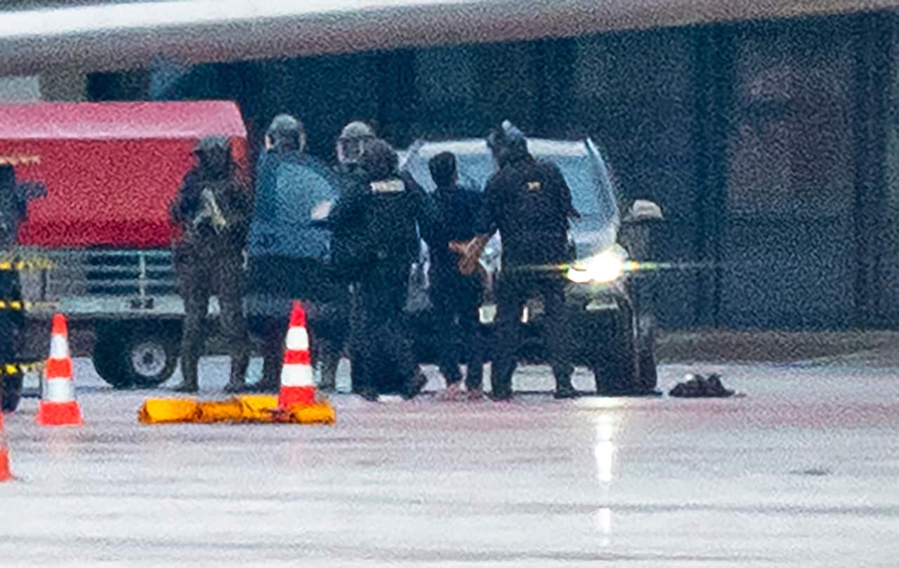 Police surround a man in handcuffs.