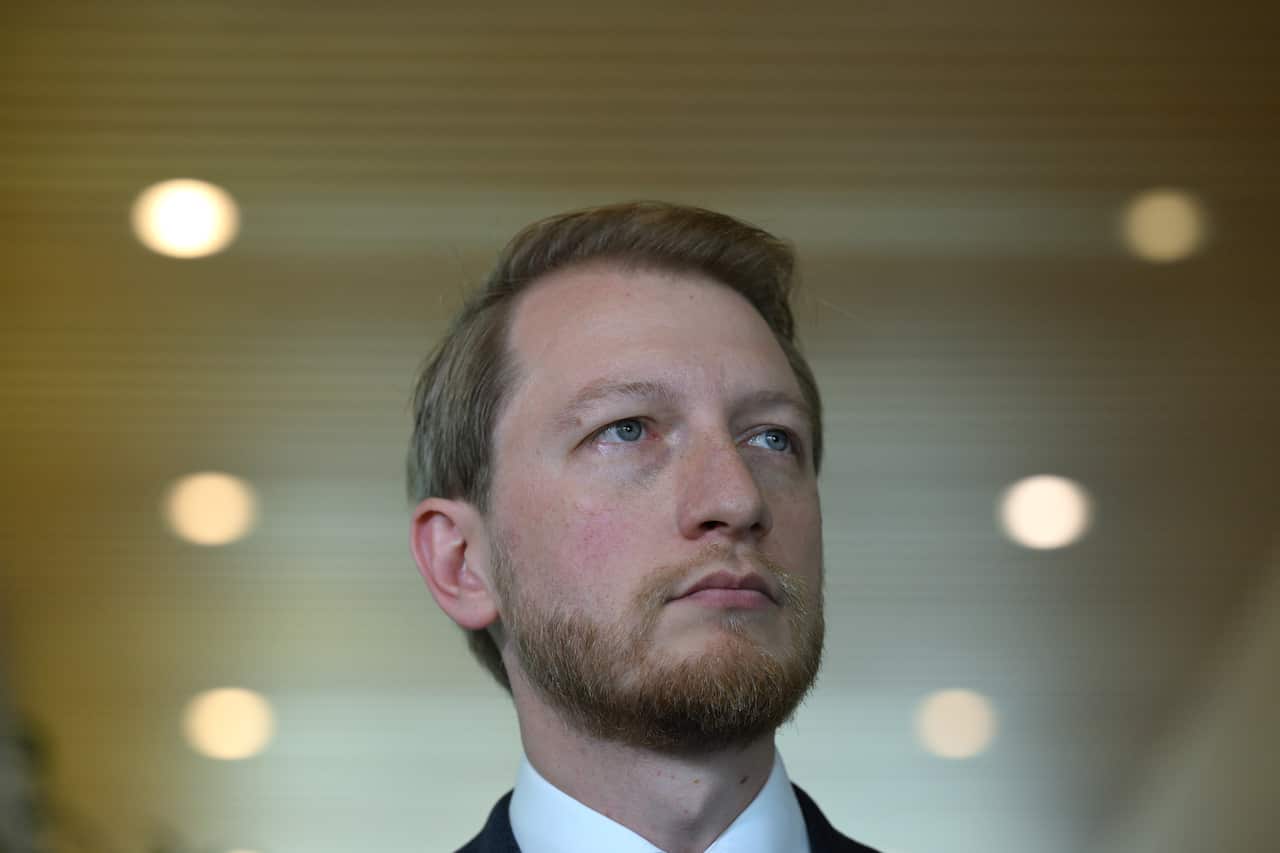 Man in a suit with a beard looks outwards.