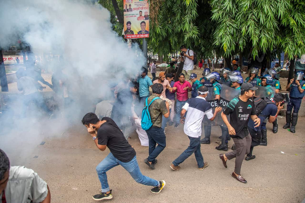 Students run from a sound grenade and tear gas used by police.