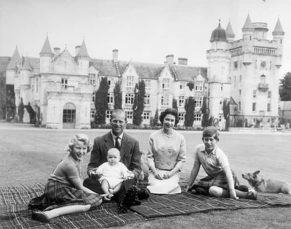 Queen Elizabeth II, Prince Philip and their young family on a rug on the grounds of Balmoral Castle.