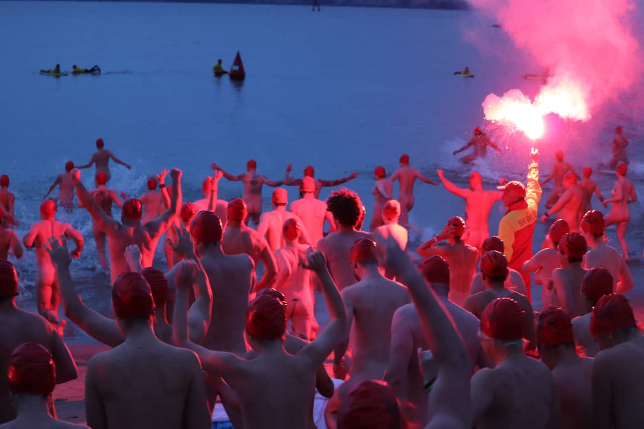 A group of people who are naked and running into the water.