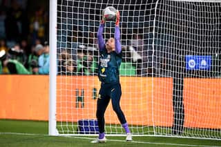 Goalkeeper Lydia Williams in the Matilda's kit, grabbing a ball from above her head standing inside the net.