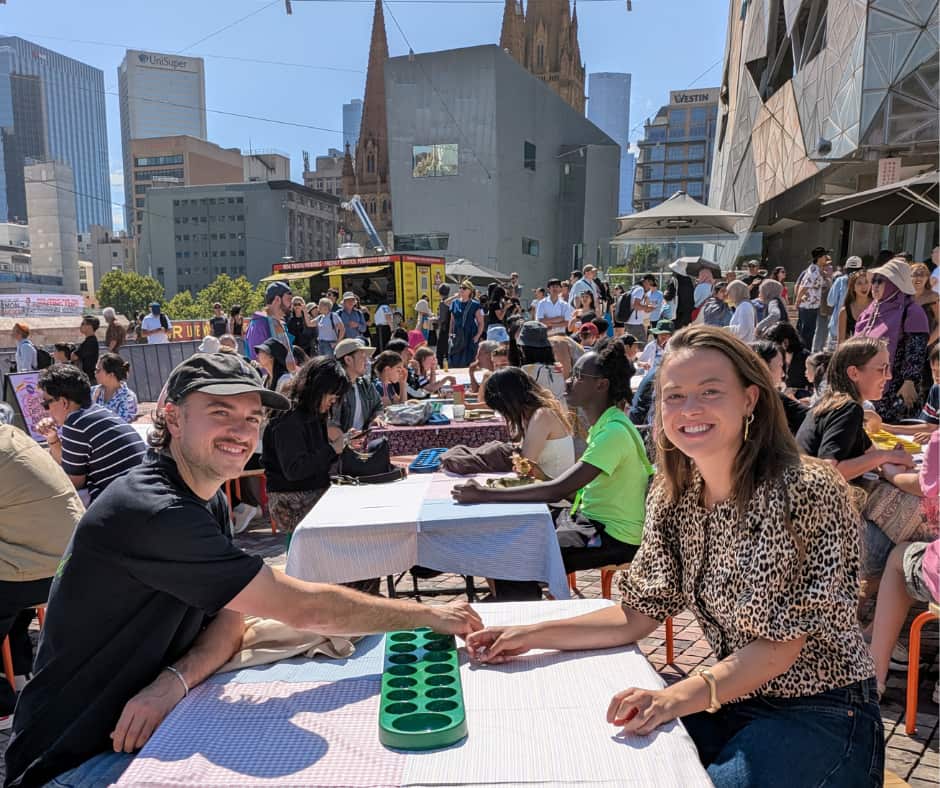 Two visitors playing congklak at the Pasar Senja event.