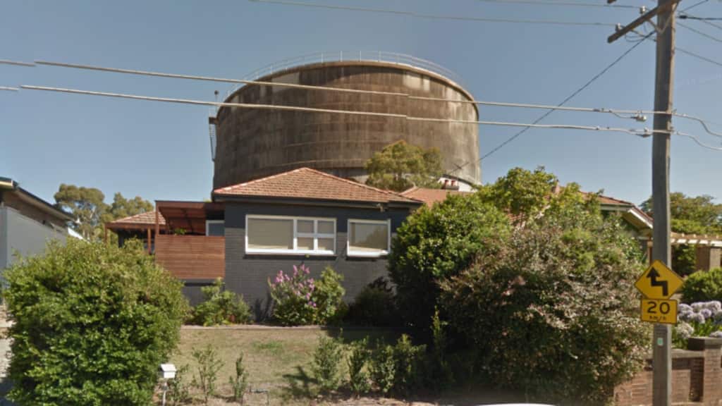 A house with a huge water tower behind it.