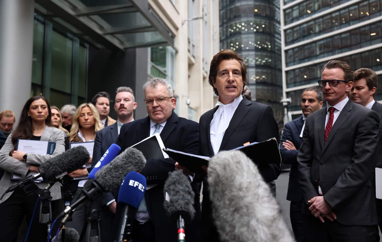 Several lawyers face microphones, reading a statement to the media.