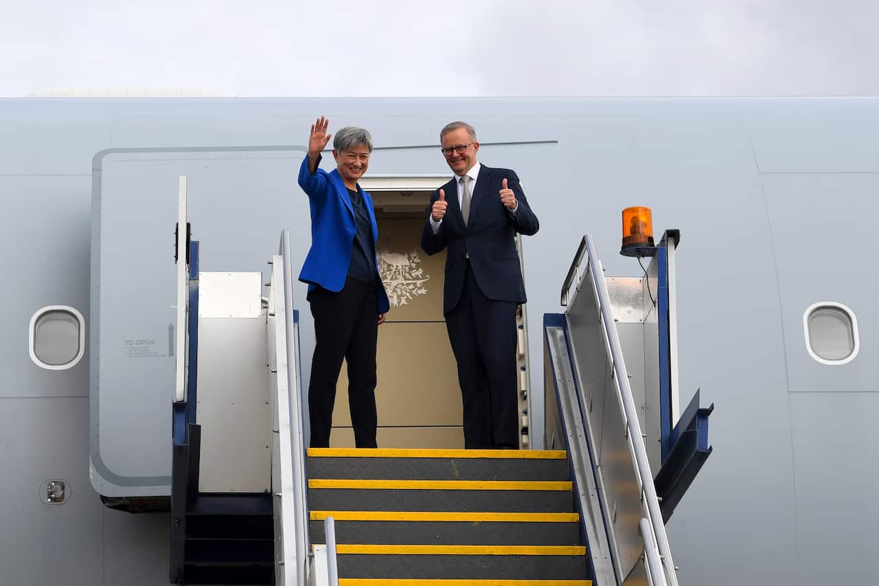 Anthony Albanese and Foreign Minister Penny Wong wave as they board a plane.