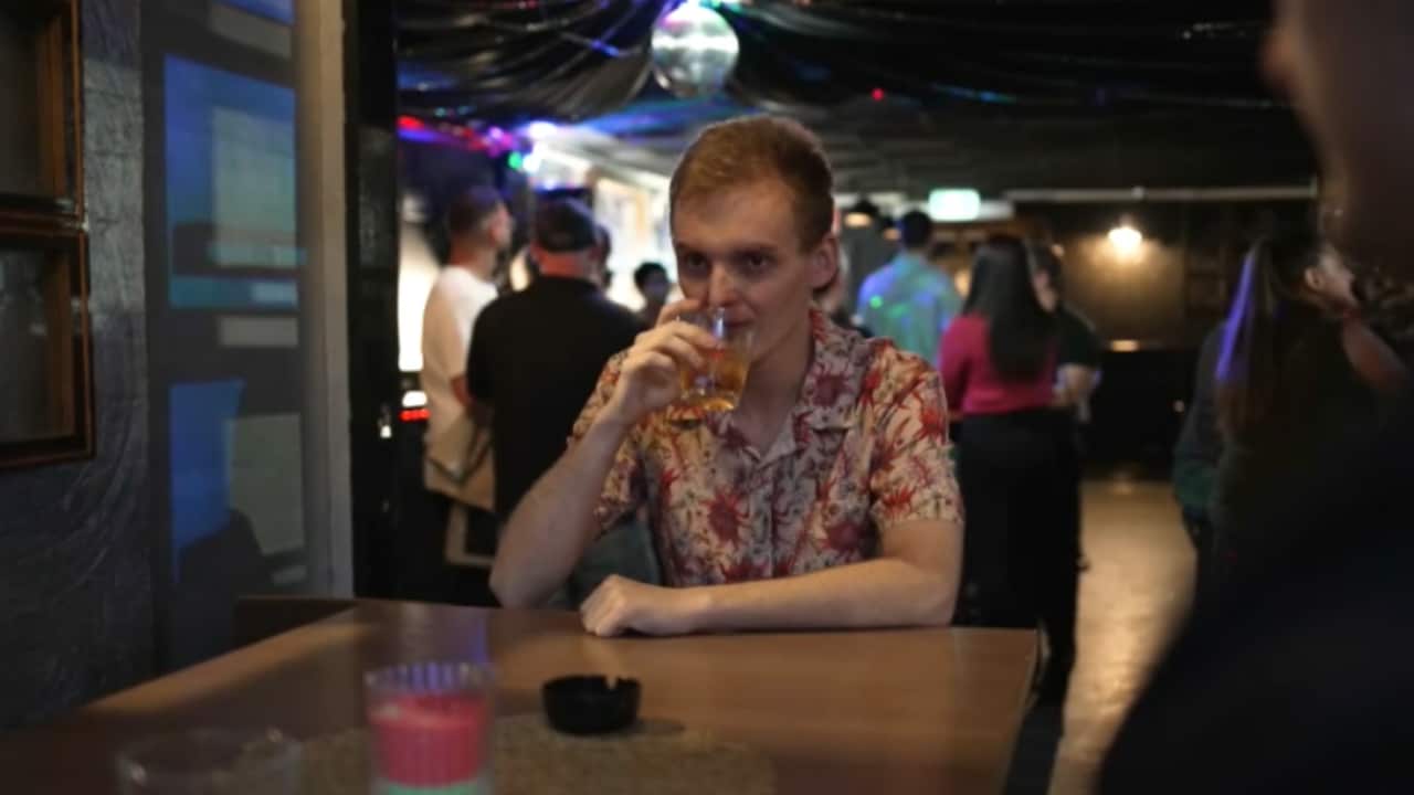 a young blond man drinks alone at a pub