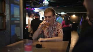 a young blond man drinks alone at a pub