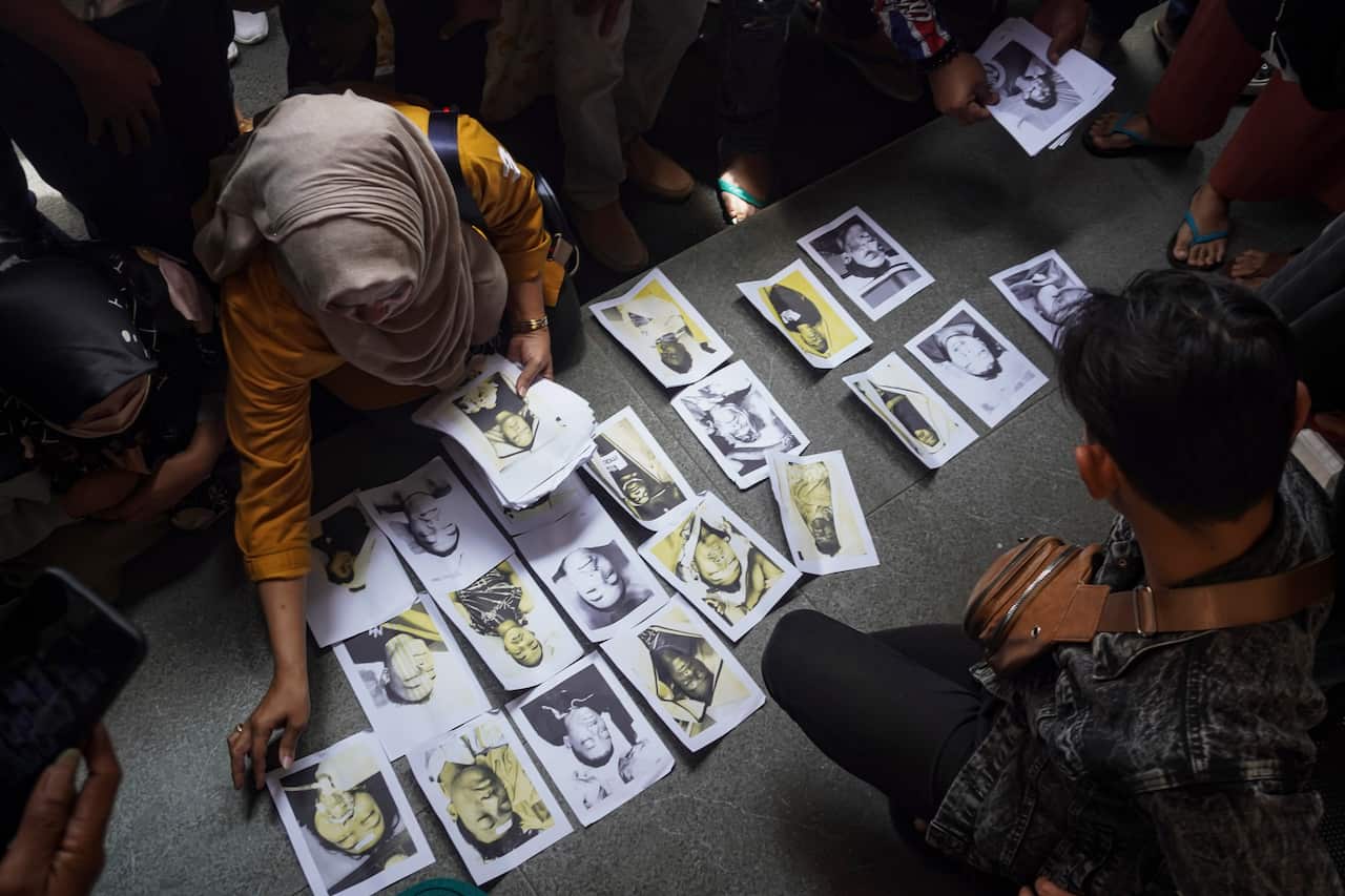 People looking for their family members inspect photographs of soccer riot victims provided by volunteers to help them identify their relatives in Malang, East Java, Indonesia.