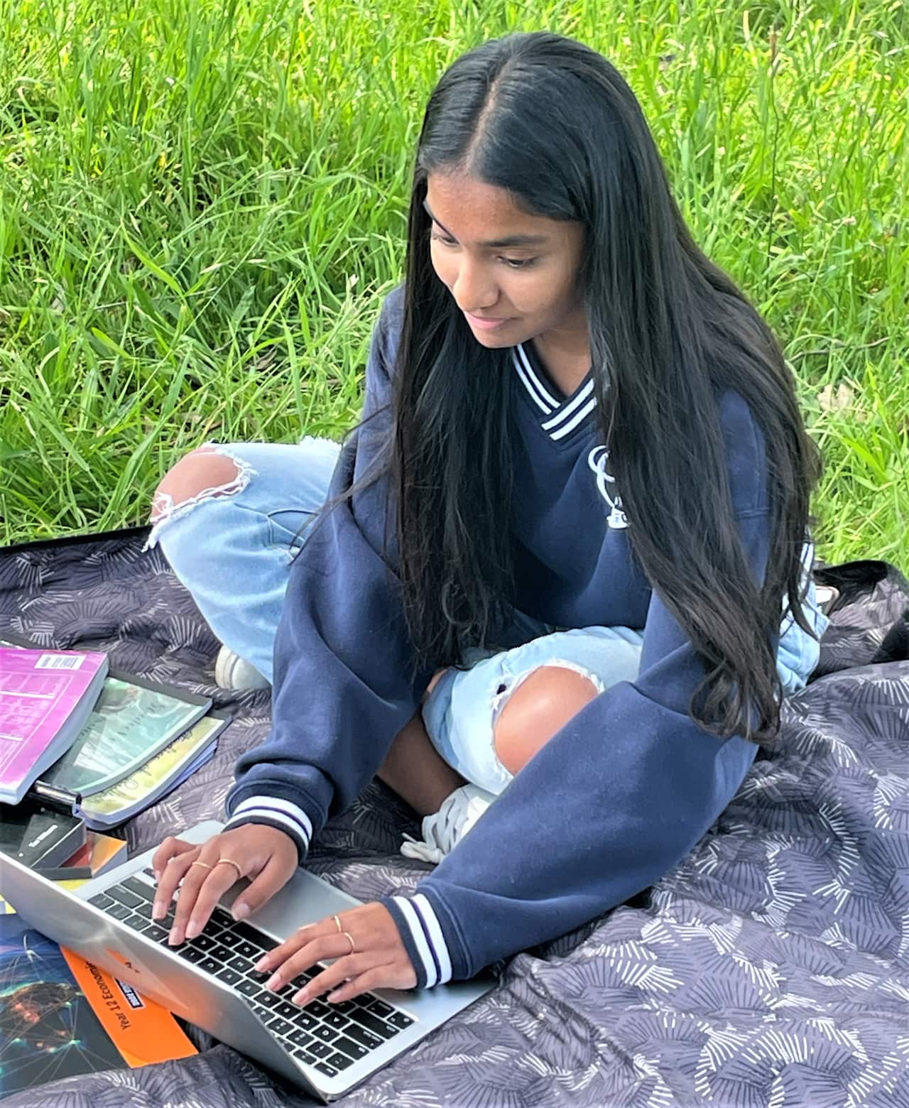 Lakshmi studying on her laptop in a park 