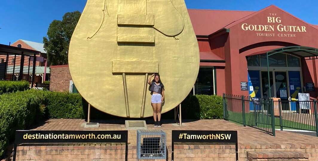 Teenage girl standing in front of the 'golden guitar' monument in Tamworth NSW