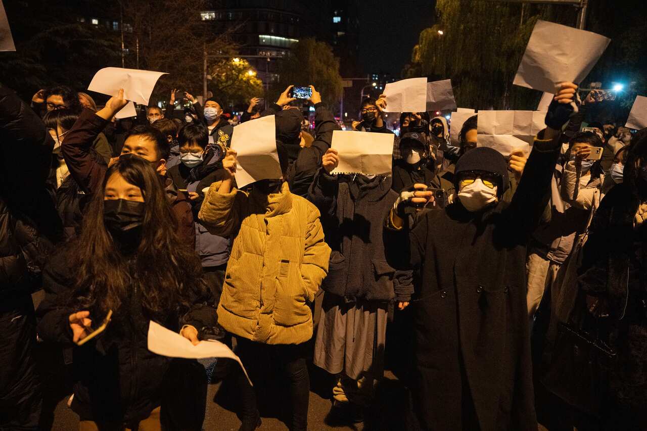 Protesters hold up blank papers and chant slogans as they march in protest in Beijing.