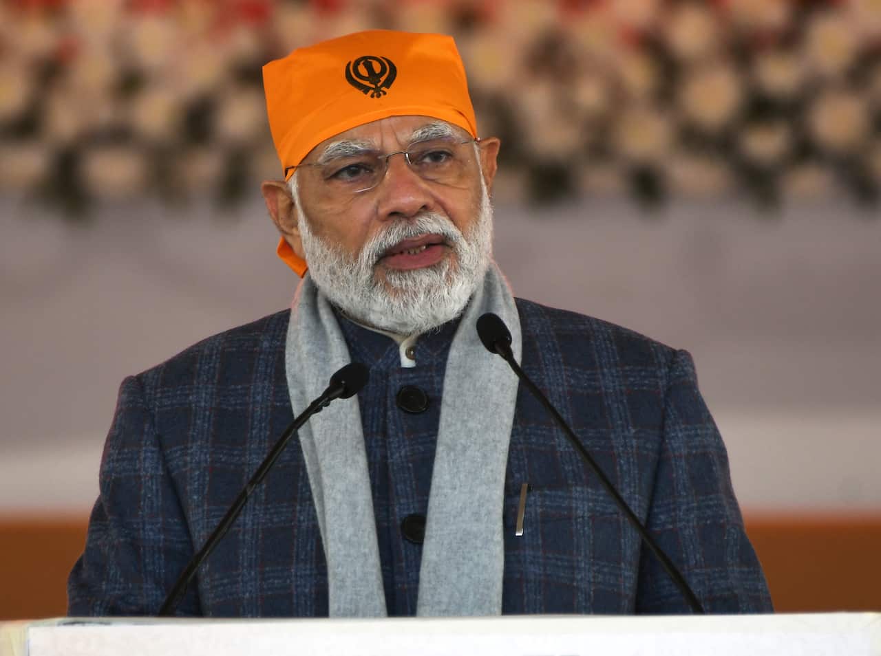 Bearded man in orange bandanna speaking at a lectern.