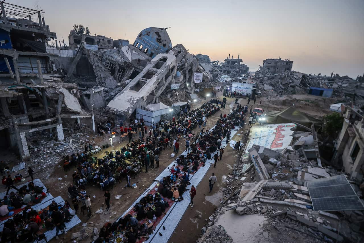 Palestinians gathered on a street for iftar amid rubble.
