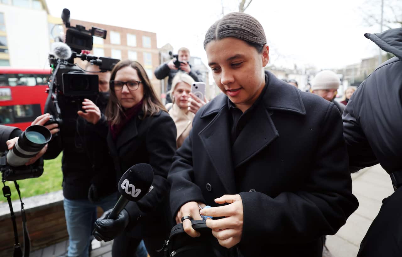 Sam Kerr arrives at a trial mobbed by media.