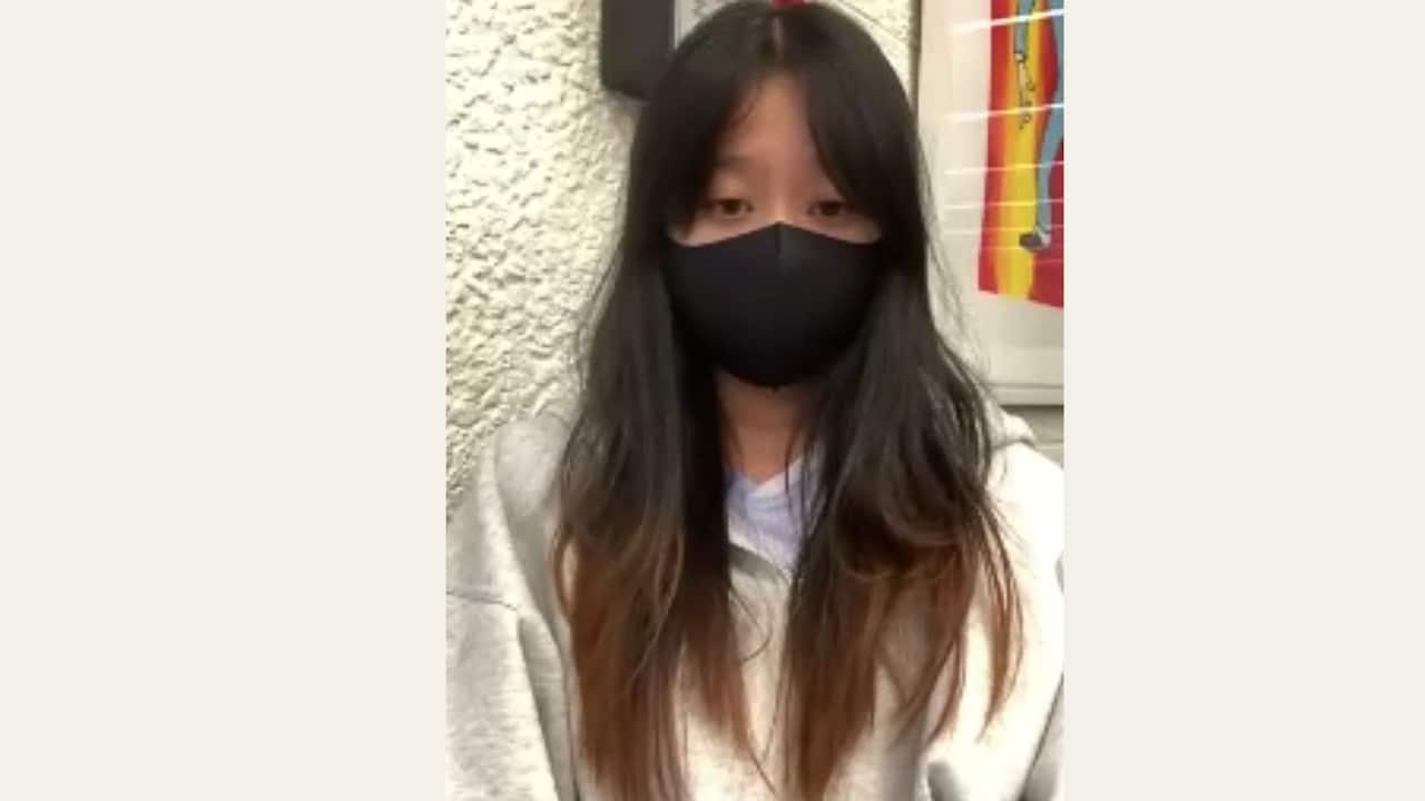 A young girl with long hair in a black mask.