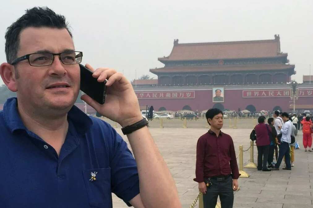 Daniel Andrews answers the phone in front of Tiananmen Square. 
