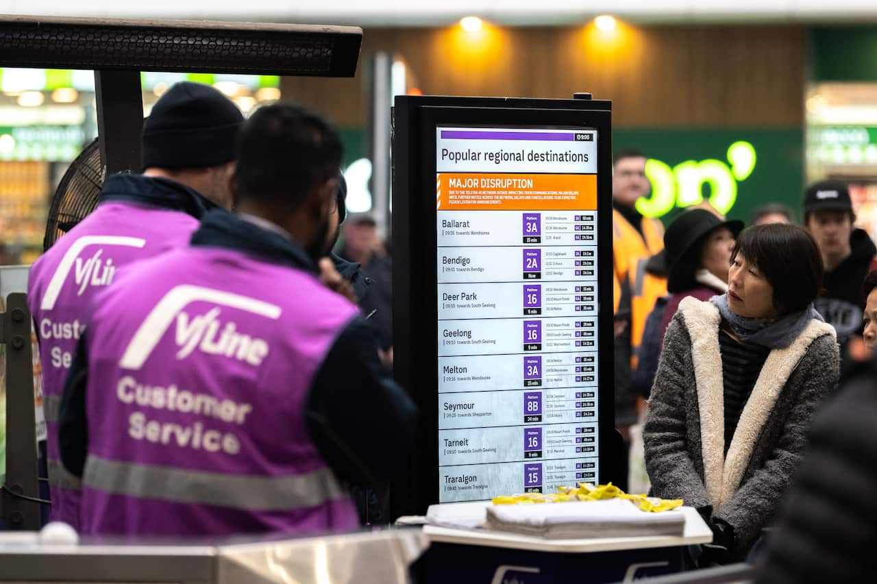 People look at an information board in a train station that reads "major delays".