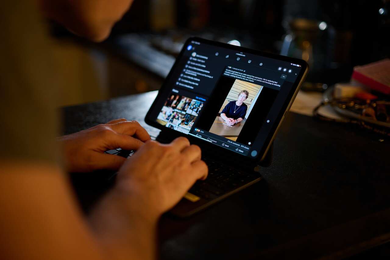A person watching a video of Mark Zuckerberg on a laptop.