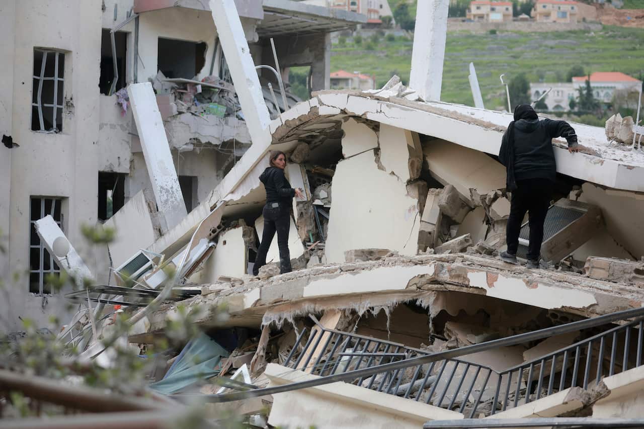Two women climbing on the rubble of a building.