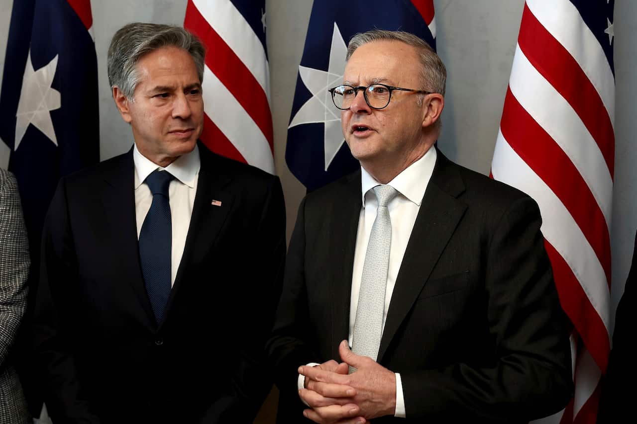 US Secretary of State Antony Blinken and Australian Prime Minister Anthony Albanese stand next to each other with the US and Australian flags behind them.