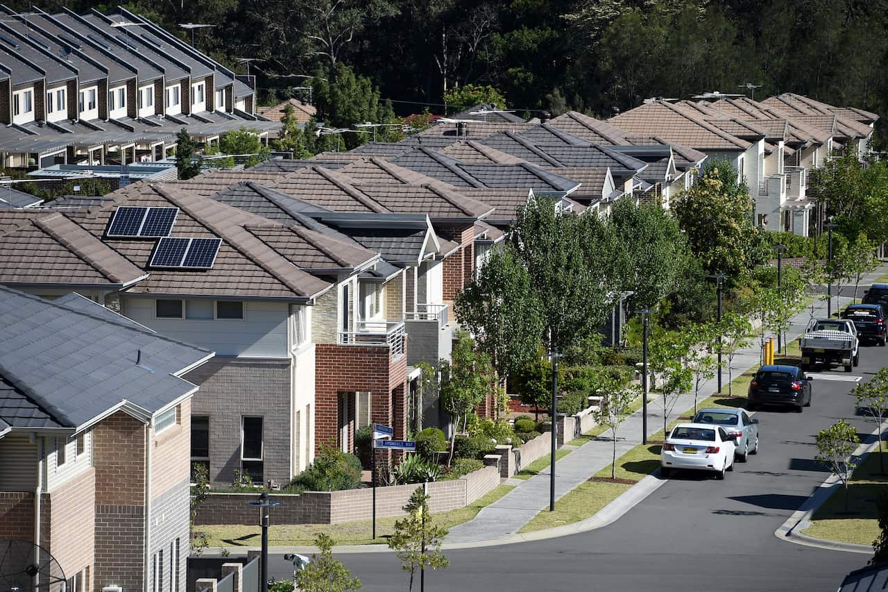 A street view showing a row of houses, with cars parked in the street.