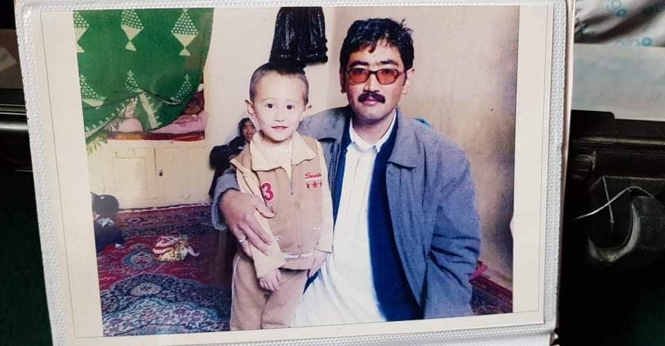 A photo of a photo of a young boy and man with his arm around the boy.