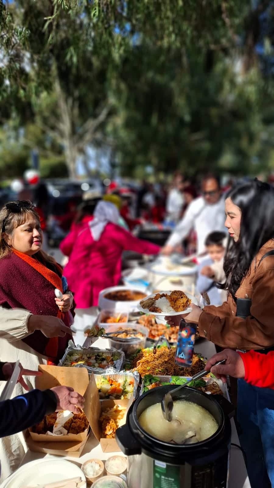 Attendees line up for traditional Makassarese dishes, including 'Ayam Palekko' and 'Bakso Nyuknyang', at the celebration.