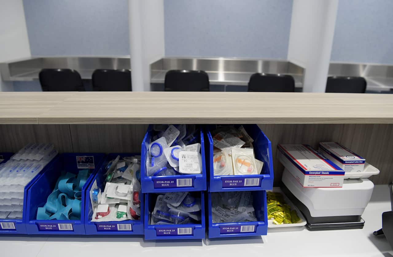 A bench with blue plastic trays containing medical supplies on it.
