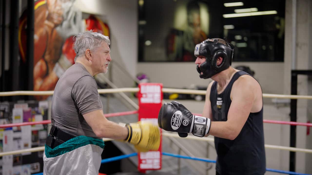 An older man boxing with younger man.