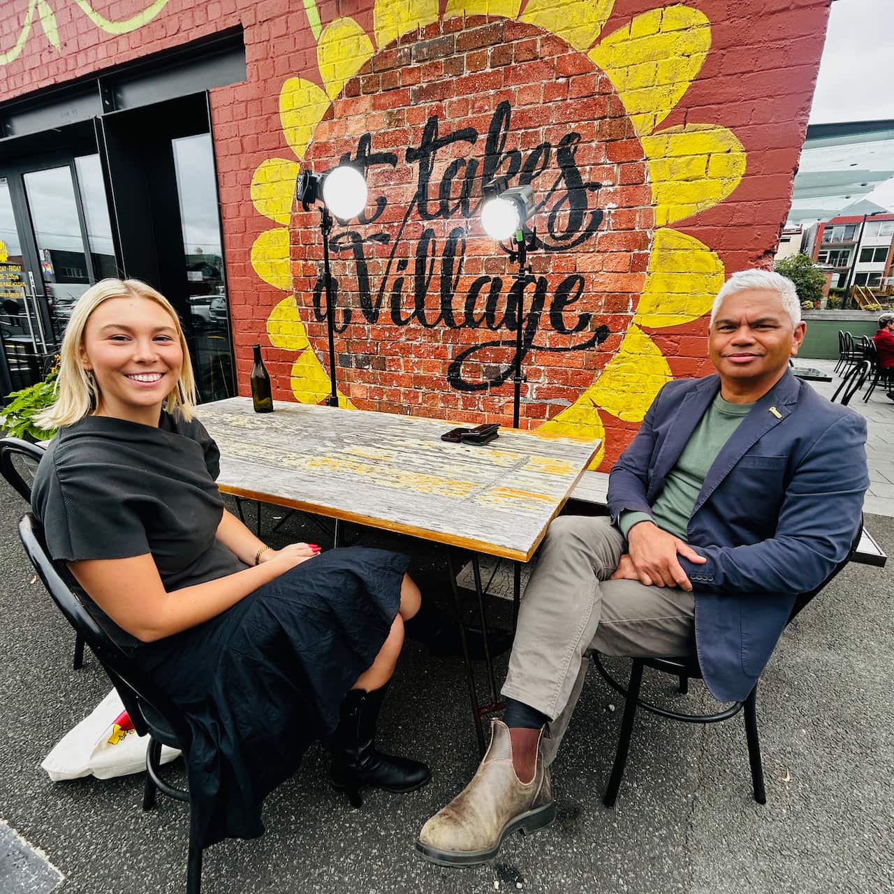A man and a woman smiling while seated at a table posing for a photo.