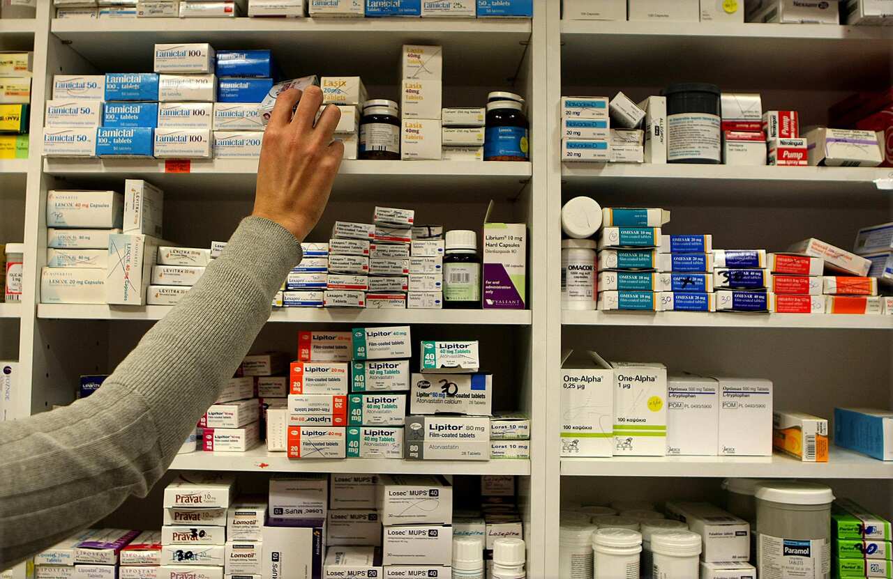 A pharmacist hand reaching for a box on medicine a shelf 