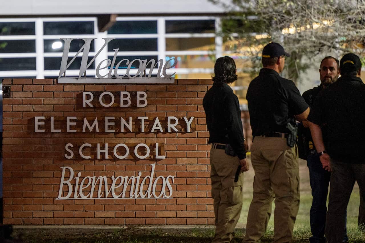 Four people are seen standing next to a sign that says "Welcome: Robb Elementary School".