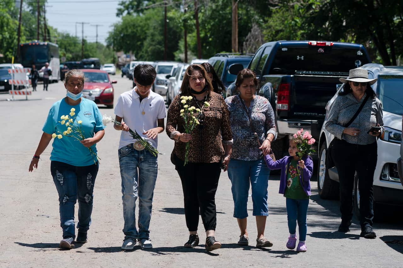 Texas school shooting mourners carrying flowers.