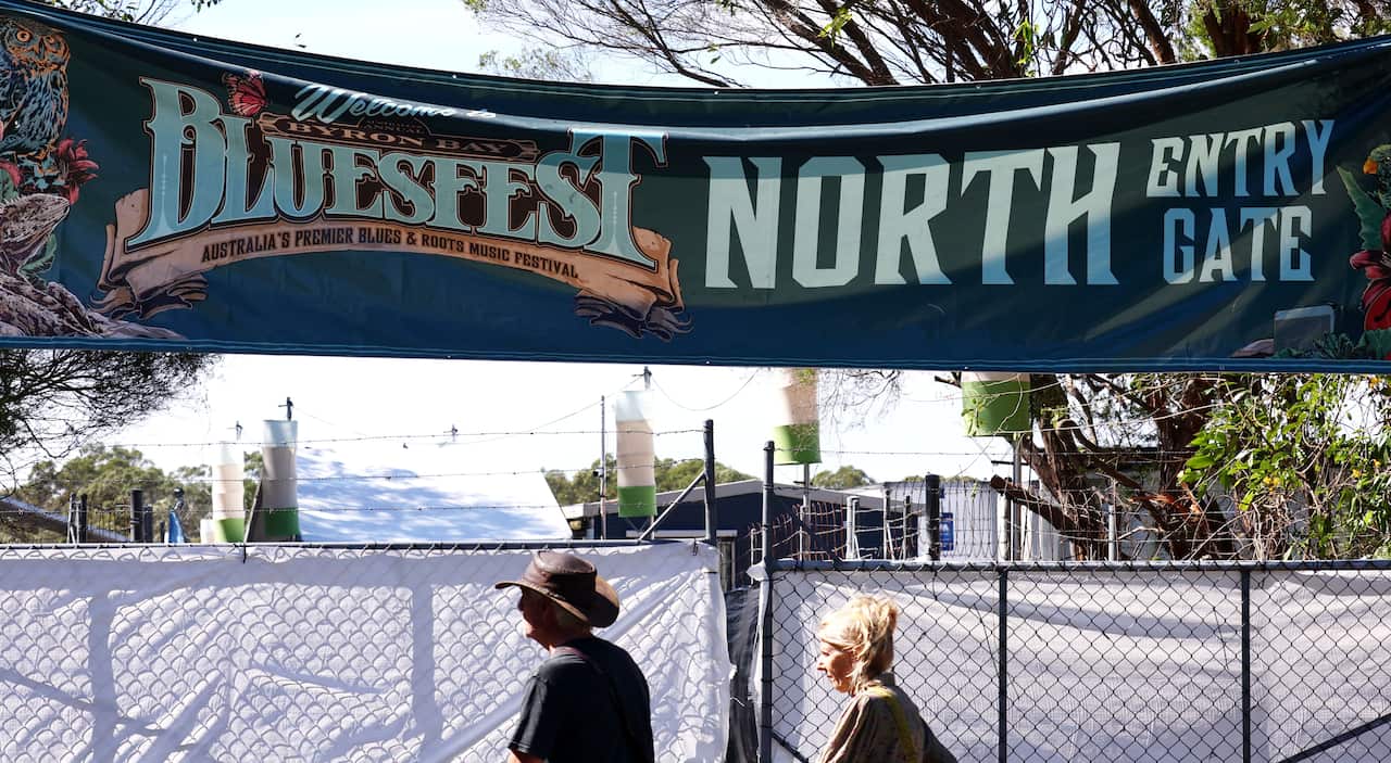 A large sign attached to a wire fence reads: WELCOME TO BLUESFEST, AUSTRALIA'S PREMIERE BLUES AND ROOTS FESTIVAL / NORTH ENTRY GATE.