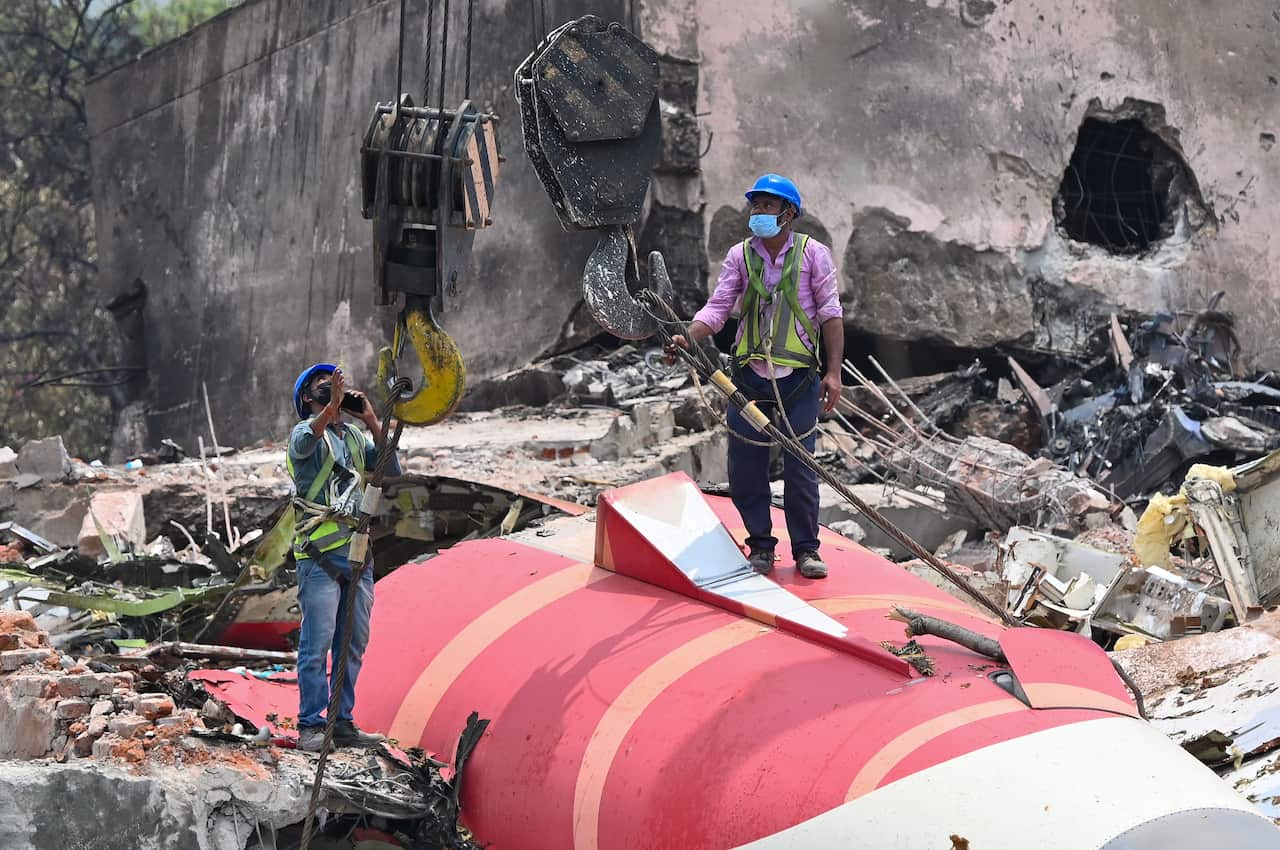 The wreckage of the crashed Air India plane is being lifted by a crane from the roof of the BJ Medical College mess building