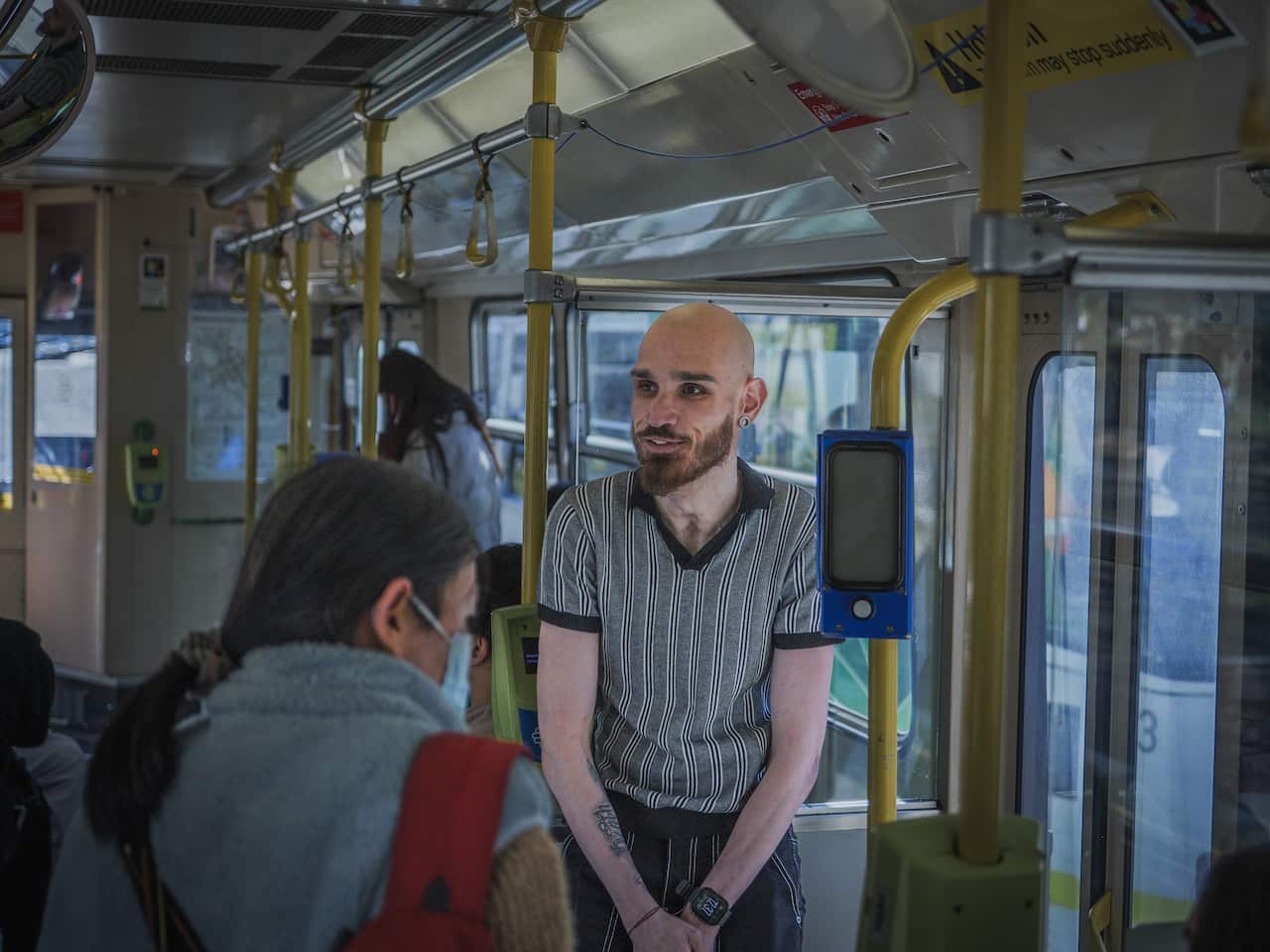 A man stands on a tram in Melbourne. 
