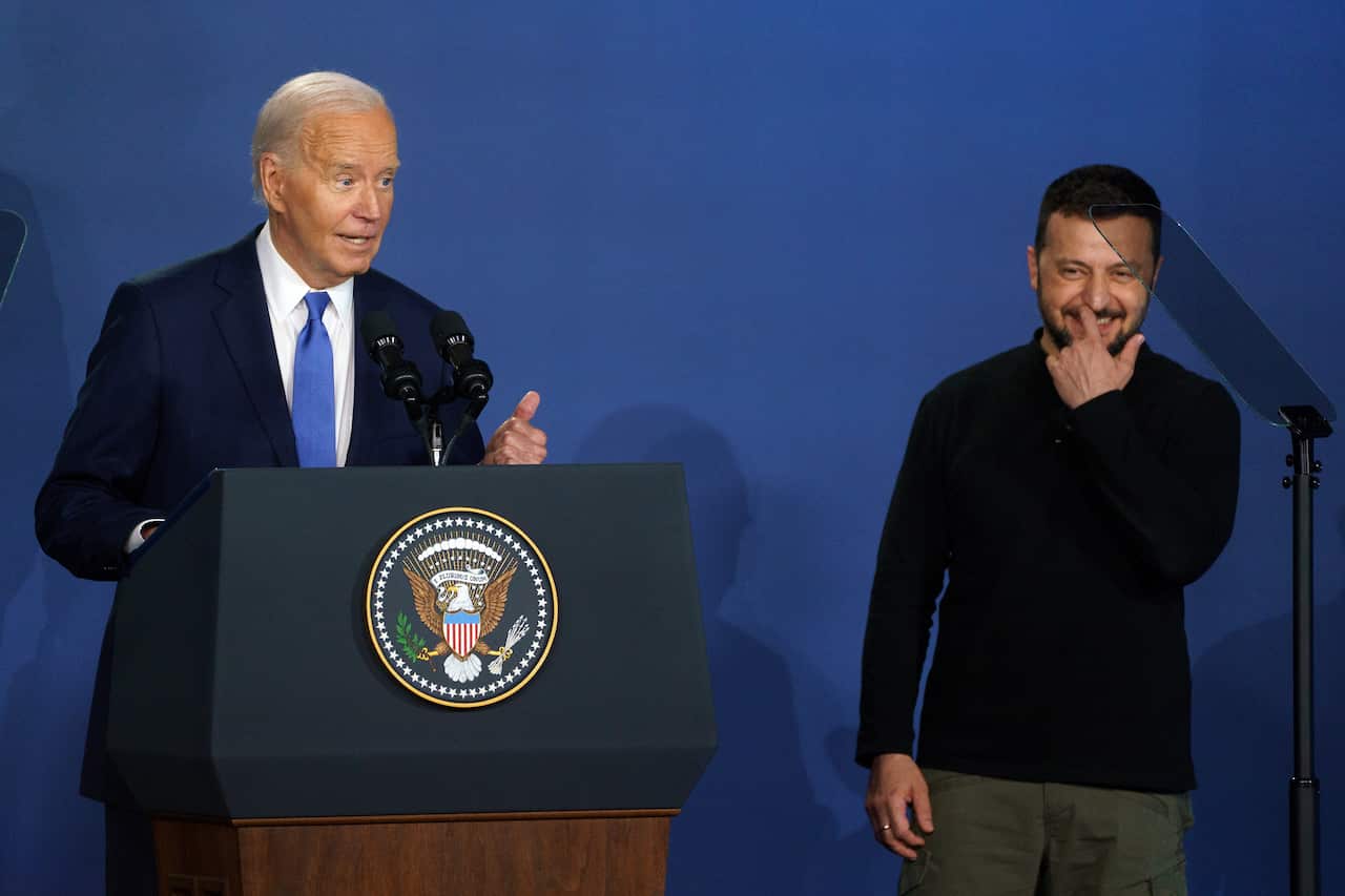 Joe Biden and Volodymyr Zelenskyy stand before a lecturn