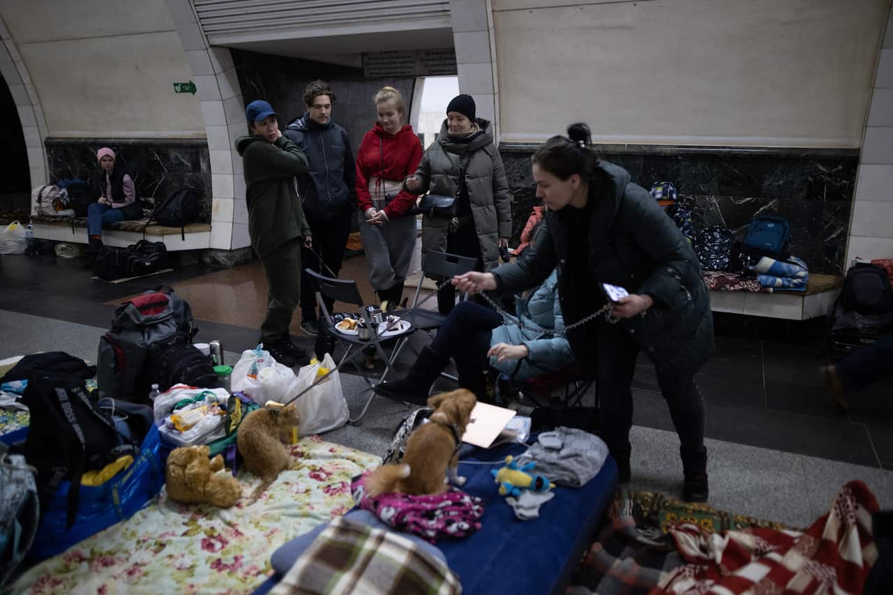Several people and two dogs are seen at an underground metro station.