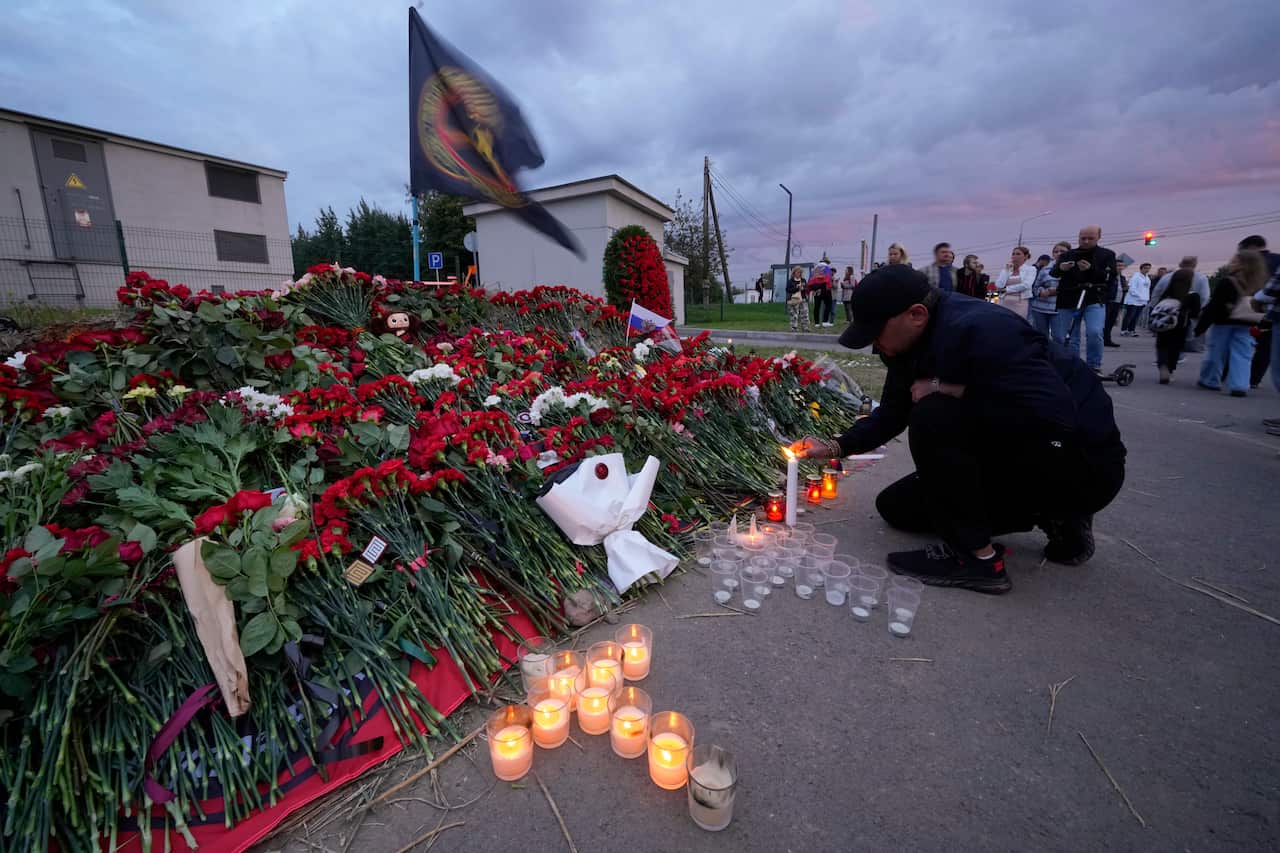A man lights a candle in front of a tribute for Yevgeny Prigozhin.