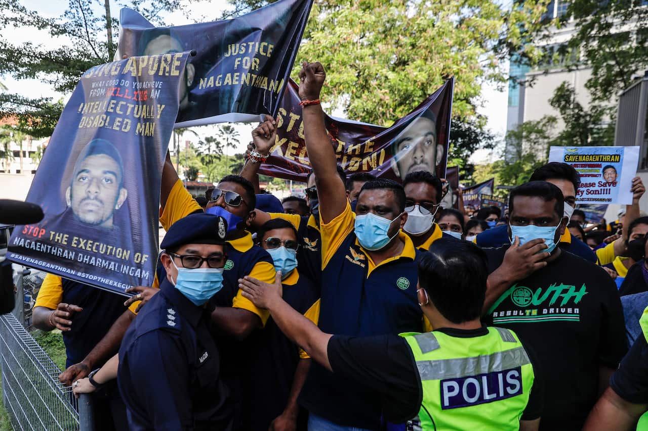 Protesters hold placards and banners as police hold them back. 