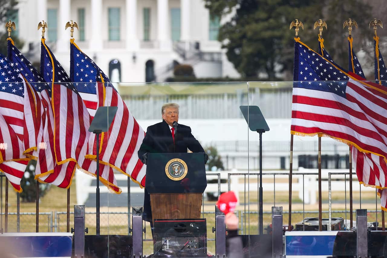 Trump stands at a podium with American flags.