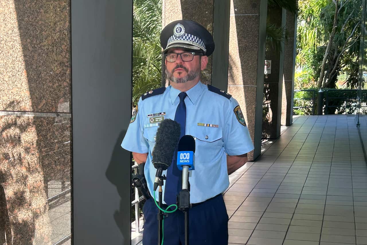 A police officer speaks to journalists outside a police station. 