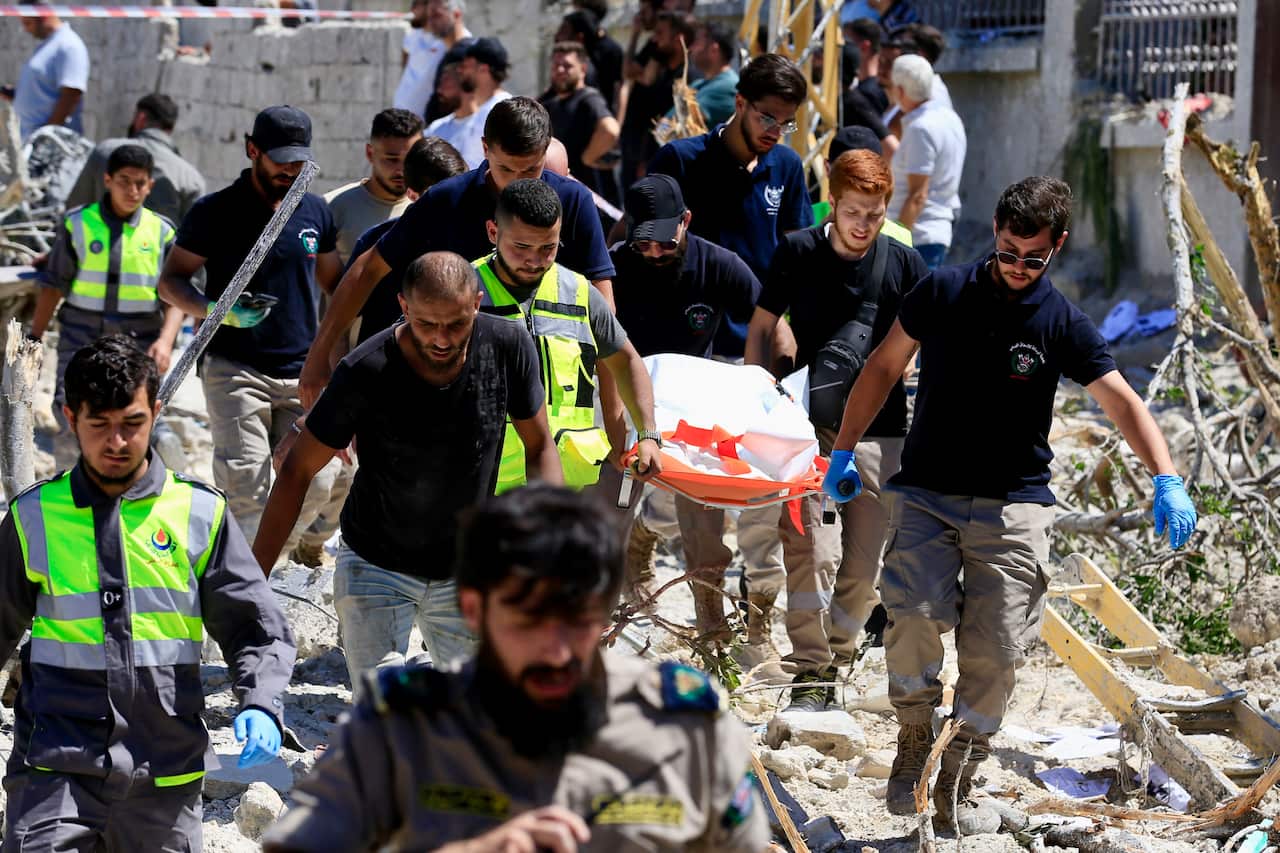 Rescuers recover a body from the rubble of an airstrike on the town of Qannarit, Sidon district, southern Lebanon